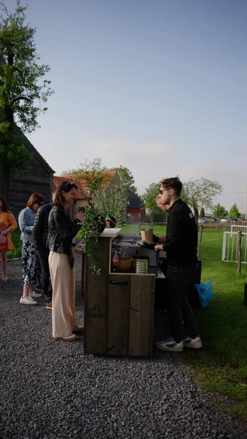De bar in een tuin tijdens een feest, gasten schuiven aan