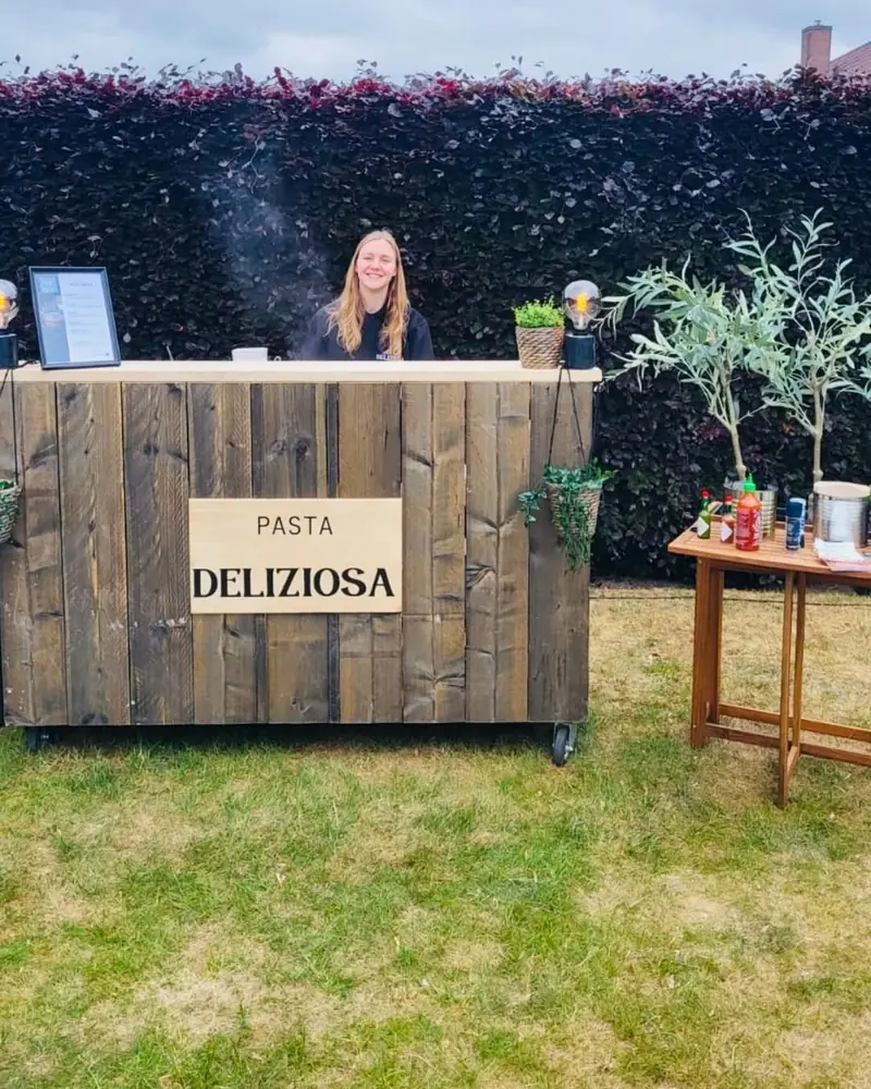 Stijgerhouten bar van Pasta Deliziosa op het gras in een tuin in Wielsbeke
