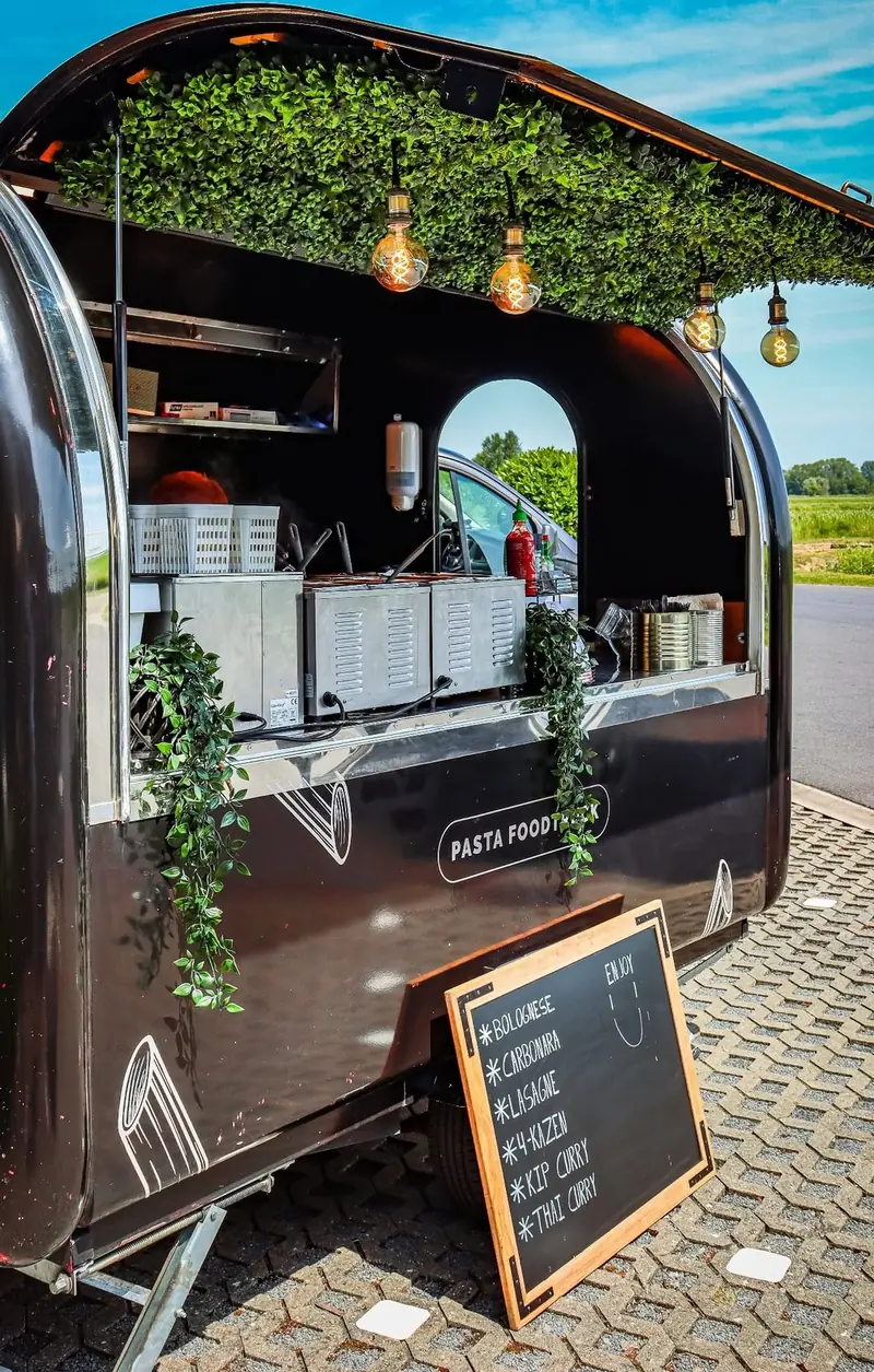 De foodtrailer van Pasta Deliziosa bij FAAC Benelux, met lampjes en een krijtbord met de sauzen
