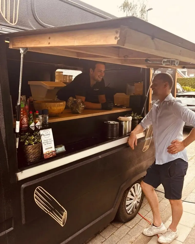 Een gast praat met de kok aan het venster van de oldtimer