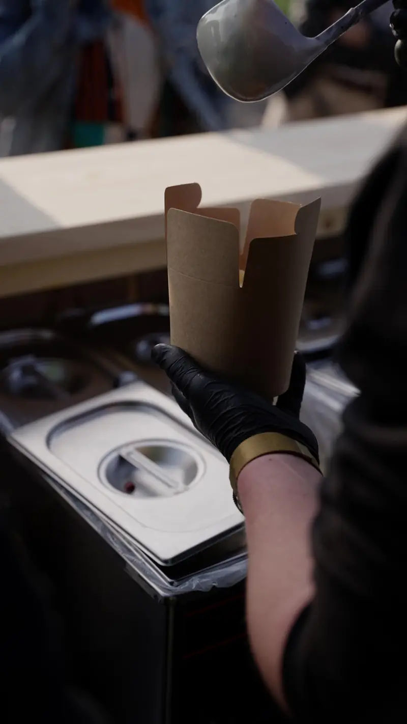 Saus wordt met een pollepel in een pastabox geschept