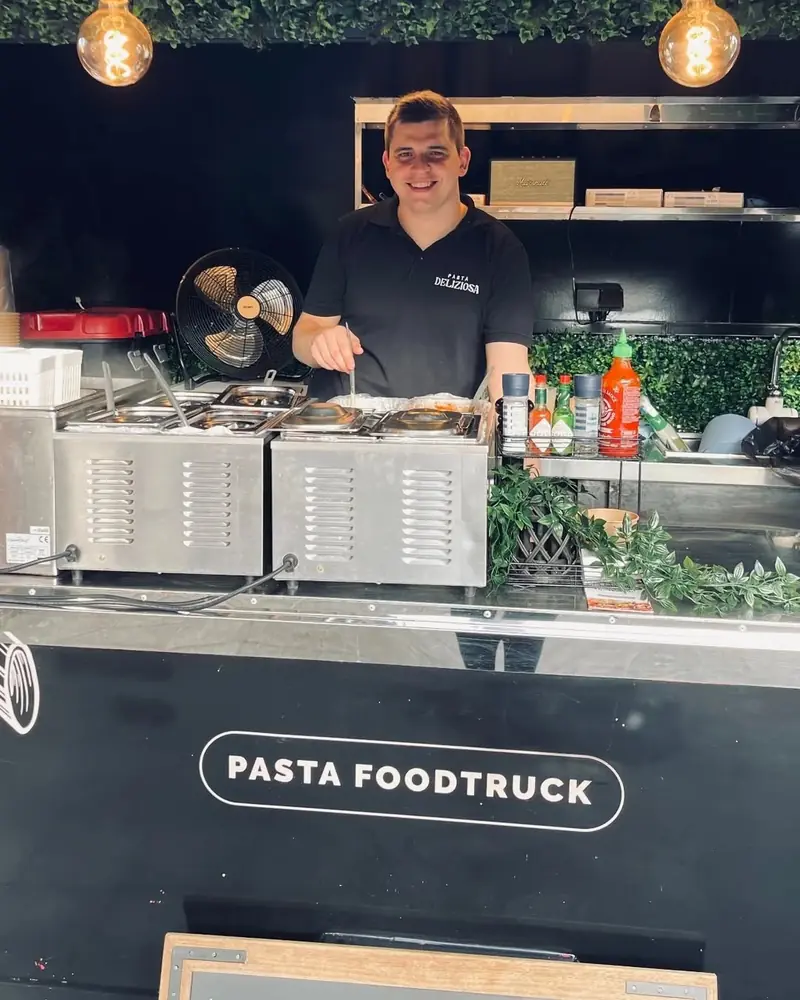 Lachende kok achter de toog van de foodtrailer bij de Centrumschool in Wingene