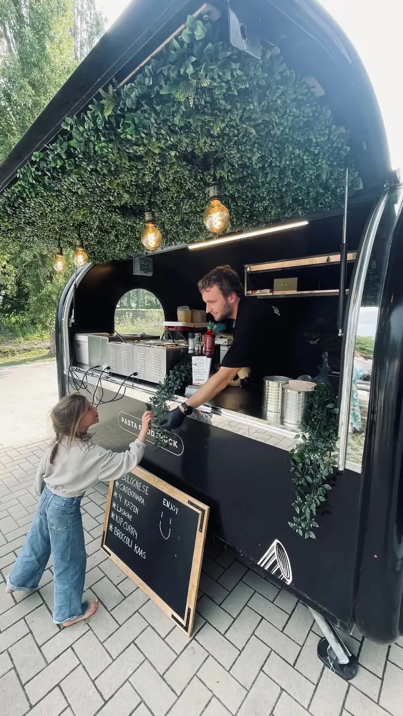 Een kind bekijkt het sauzenbord aan de foodtrailer