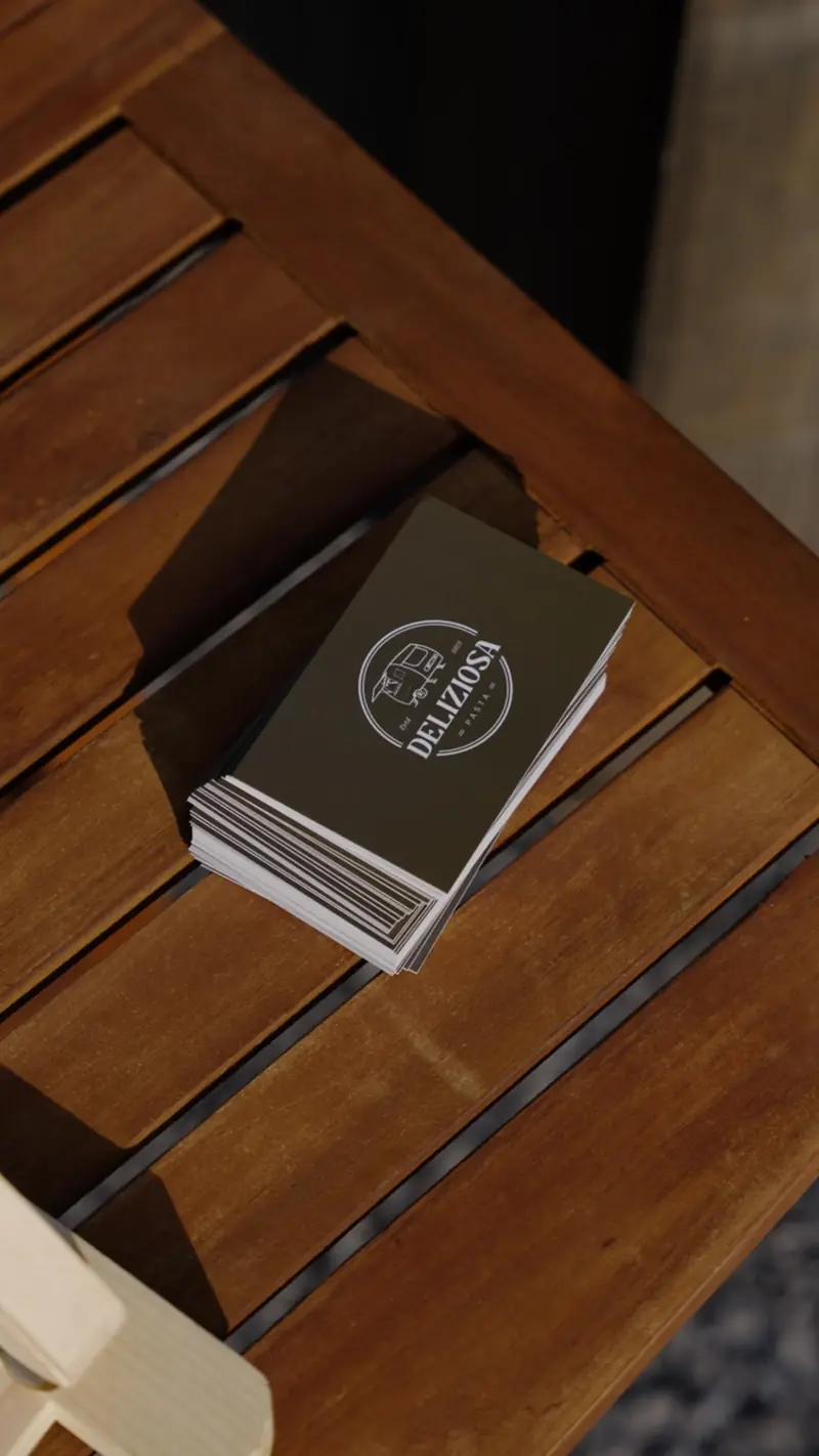 Visitekaartjes van Pasta Deliziosa op een houten tafel